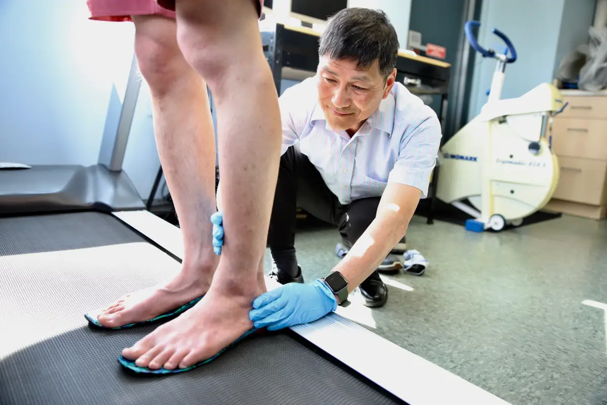 Dr. Lai examining a patient's foot and ankle in the clinic