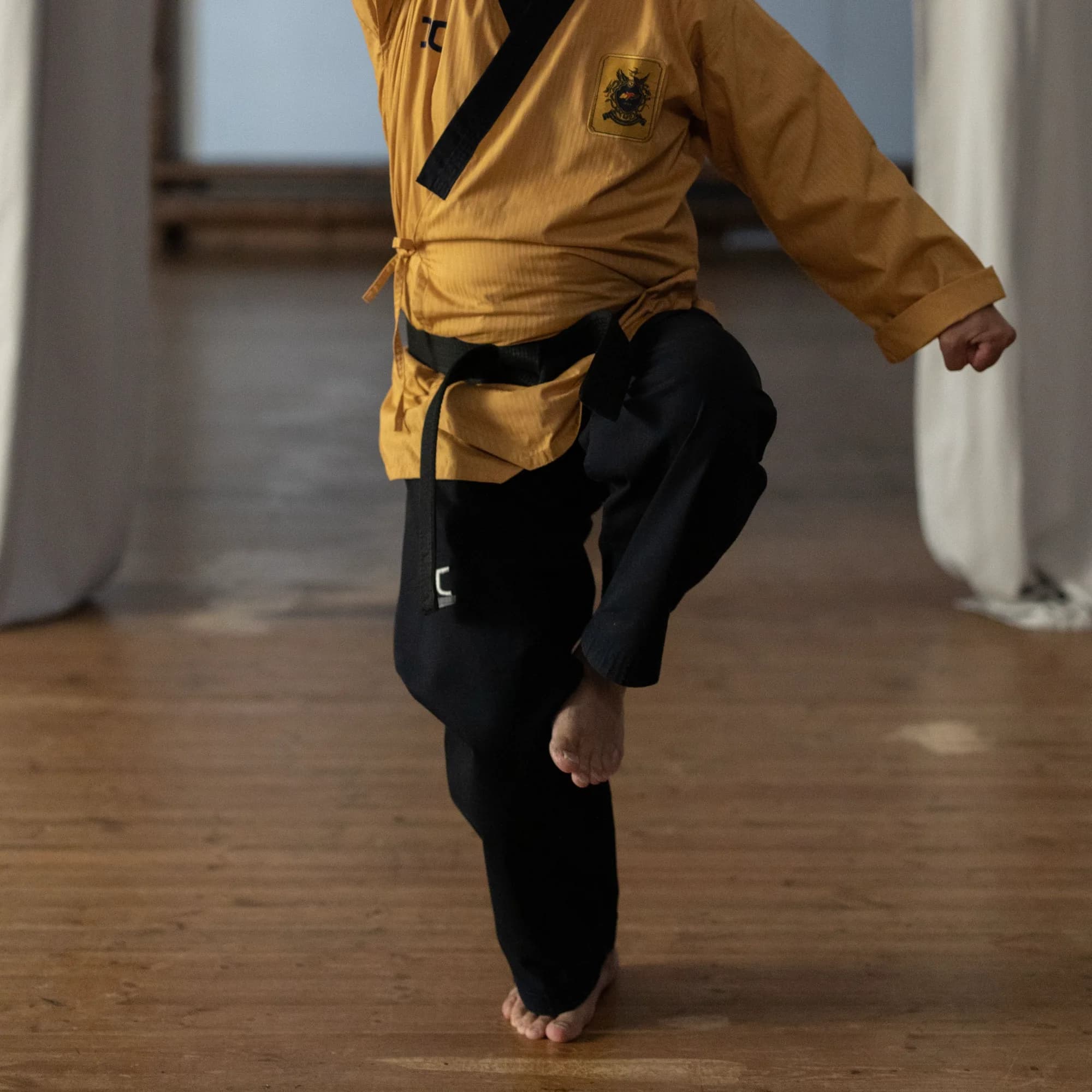 A martial artist balancing on one bare foot