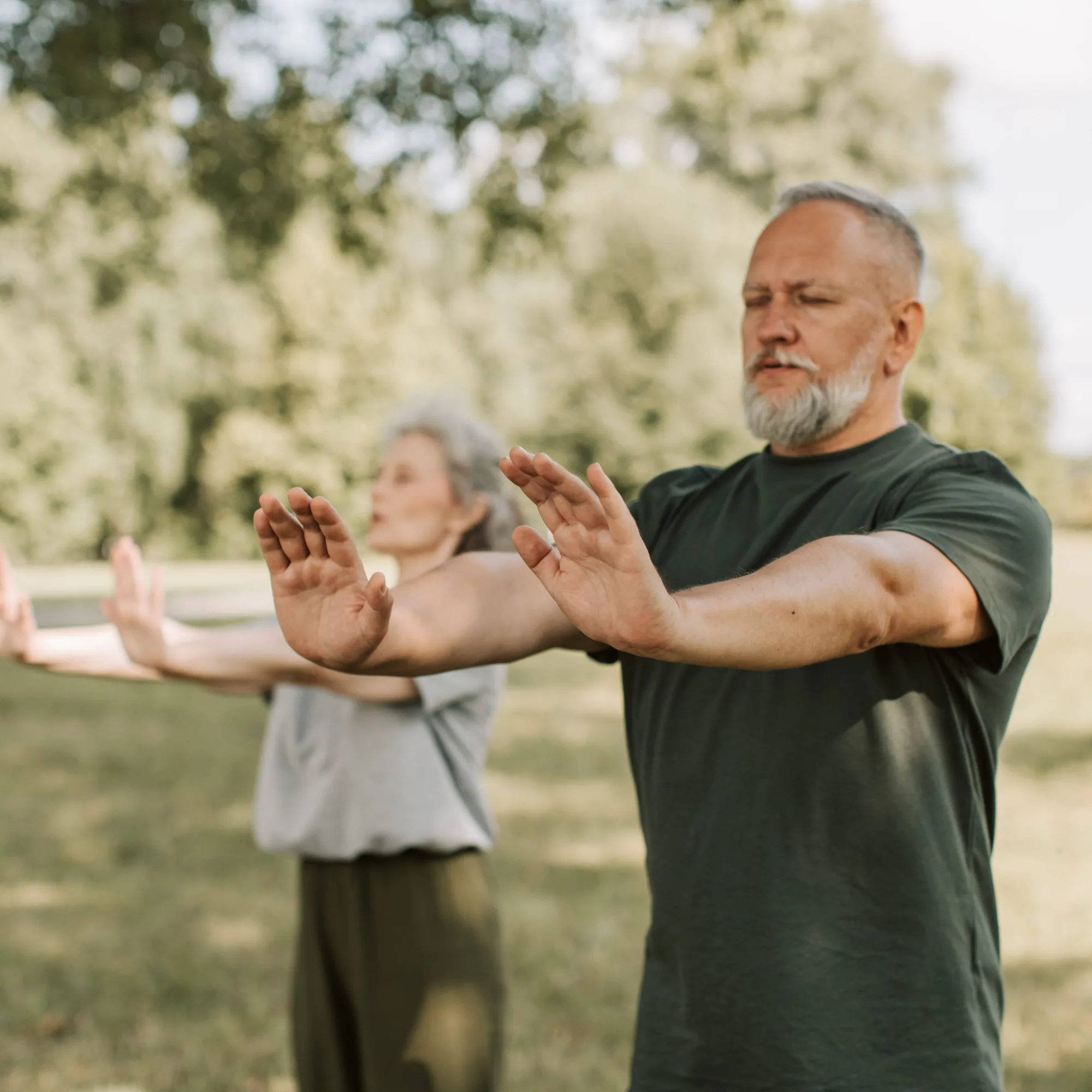 Older couple practicing gentle movement outdoors in a park